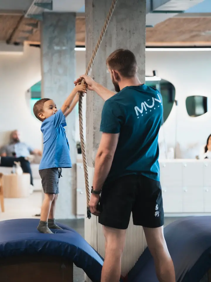 Tréner v tričku MÜV Academy pomáha chlapcovi chytiť lano